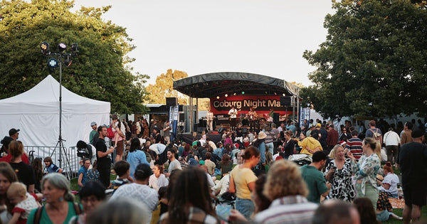 Crowd gathered in front of the Coburg Night Market stage, featuring event branding and live entertainment signage.