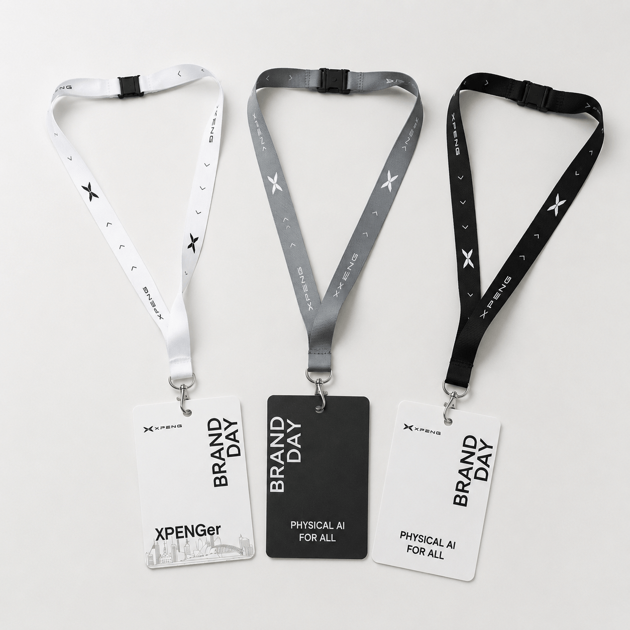 Three lanyard ID badges displayed on a light gray background. The left lanyard is white with black text and star motifs, paired with a white card.