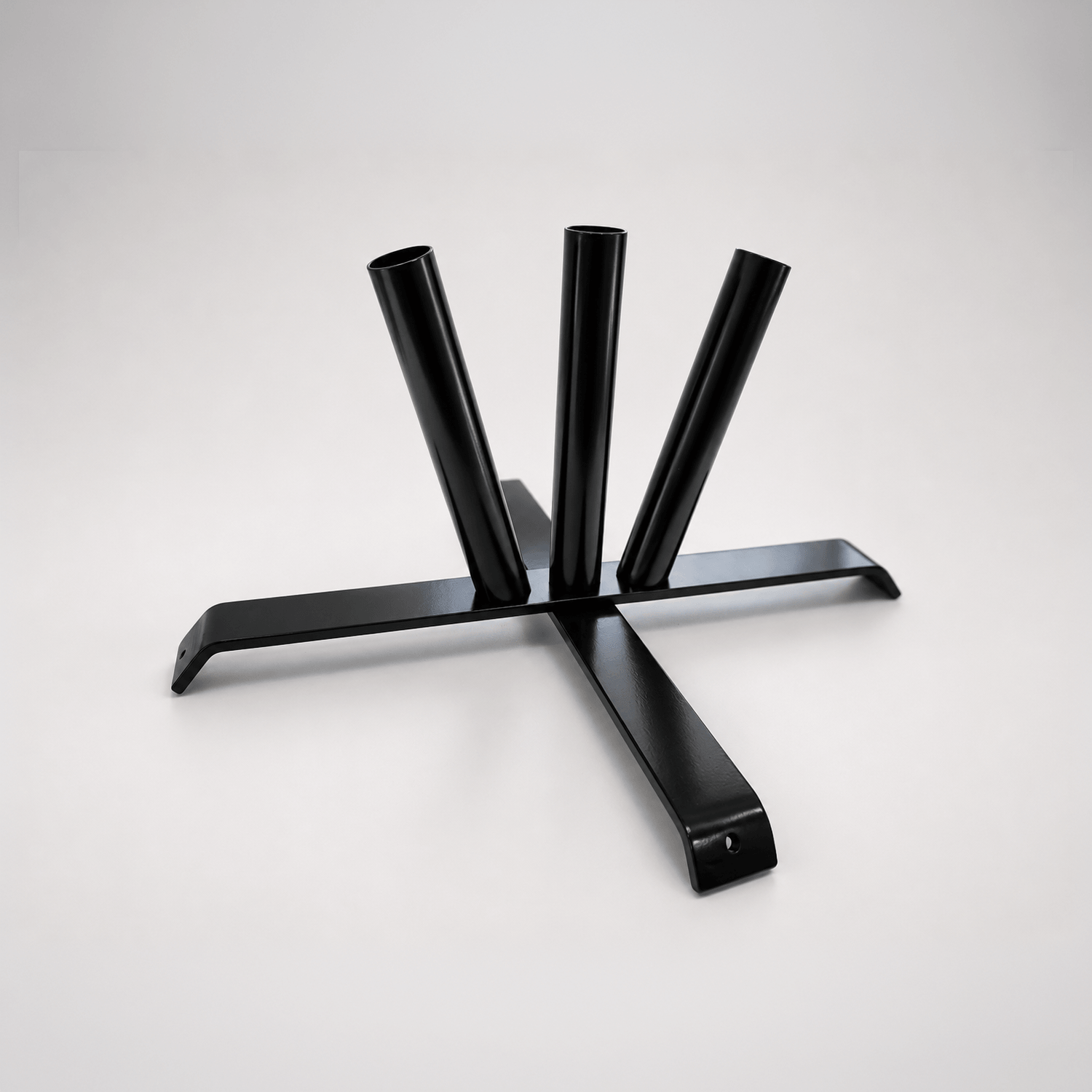 A black metal table base with three vertical cylindrical legs and a wide cross-shaped support frame, photographed on a clean light gray studio background.
