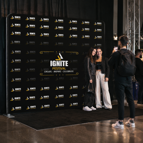 Two people posing in front of an 'Ignite Festival' branded backdrop.