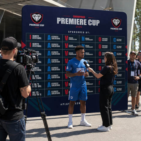 Person in blue sports uniform being interviewed by a reporter against a 'Premiere Cup' backdrop.