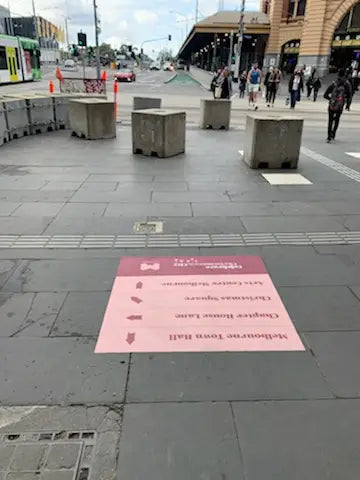 Directional floor decals near Flinders Street Station assist pedestrians with clear, branded wayfinding to Melbourne Town Hall, enhancing urban navigation.
