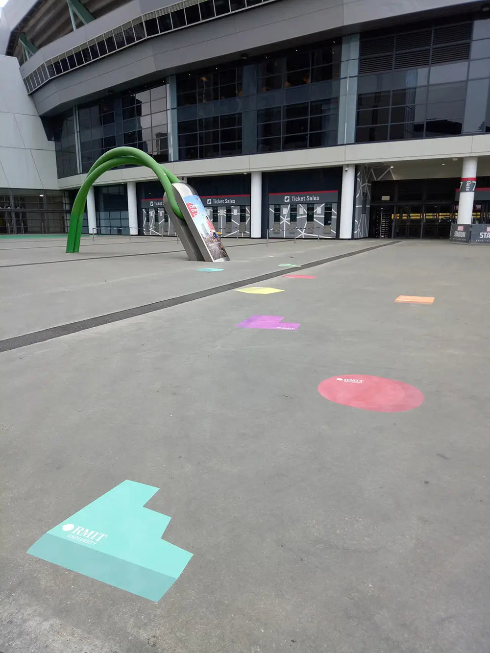 Geometric, colorful floor decals outside a university guide visitors with creative branding, blending utility and vibrant design for a memorable experience.