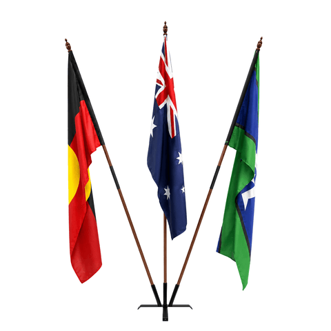 Three flags on a three-arm flagpole stand against a plain white background: the Australian Aboriginal Flag on the left, the Australian Flag in the center, and the Northern Territory Flag on the right.